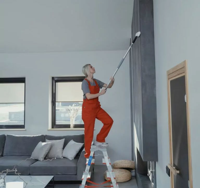 Woman dusting a high surface