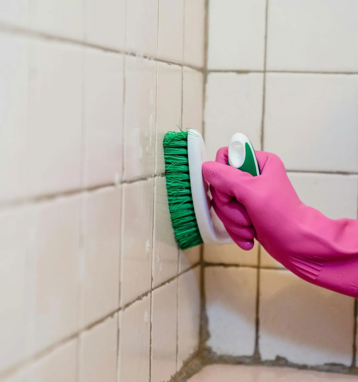 Gloved hand scrubbing tiles