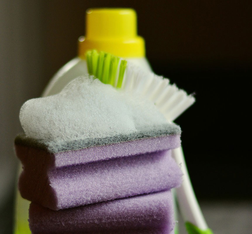 Sponges stacked next to a scrubbing brush