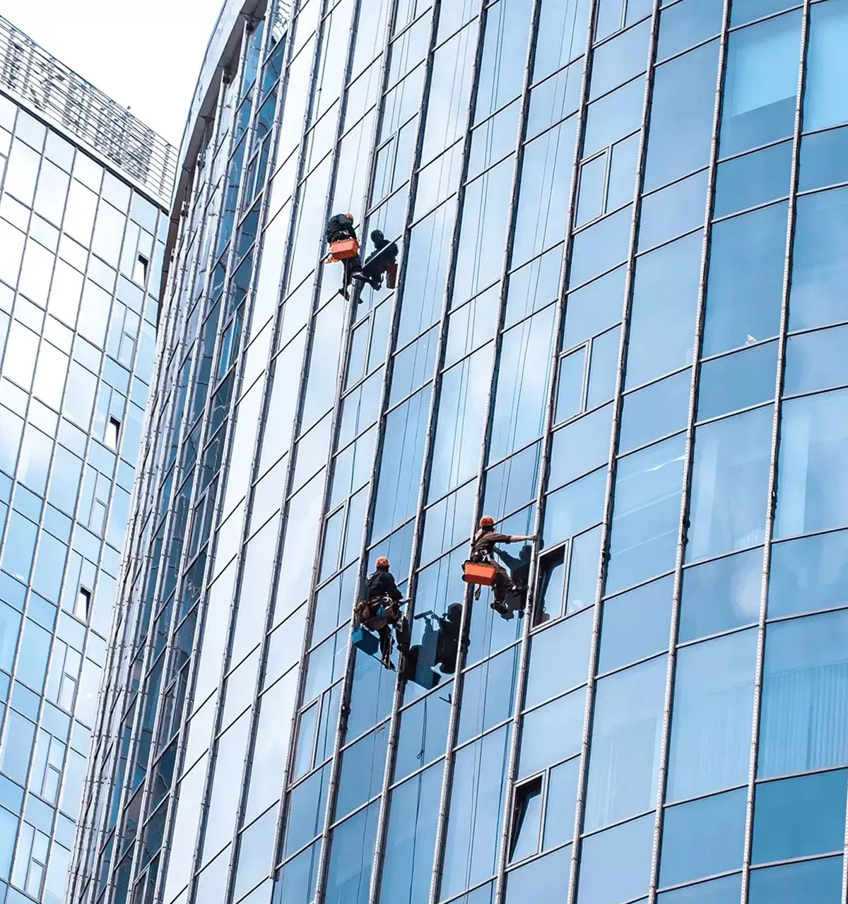 Multiple window washers on the side of a building