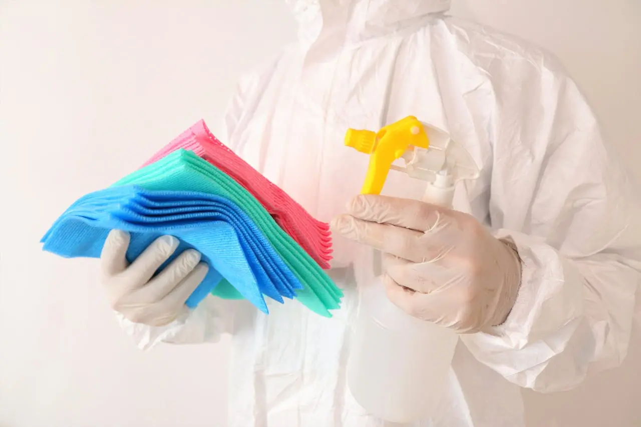 A cleaner is holding microfiber cloths and spray